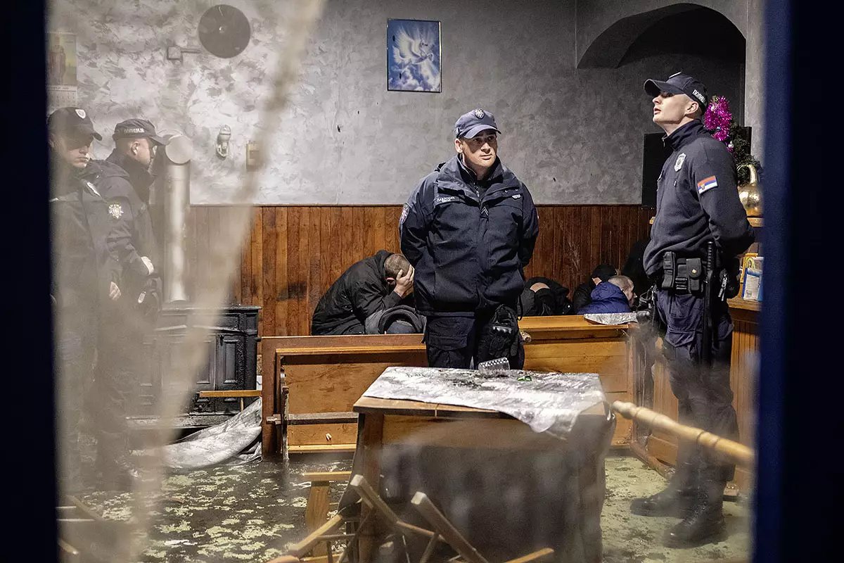Stvarna fotografija scene iz kafane u Mionici tokom lokalnih izbora, koju je načinila Zorica Popović: policajci i okupljeni ljudi u prostoriji.